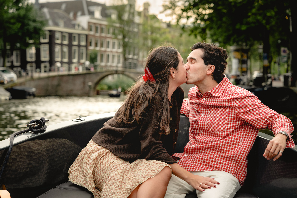 Couple cuddling on an open boat on the Amsterdam canals.

