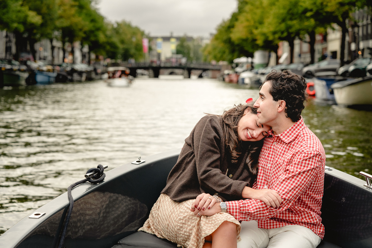 Couple celebrating their engagement with Amsterdam canal views.