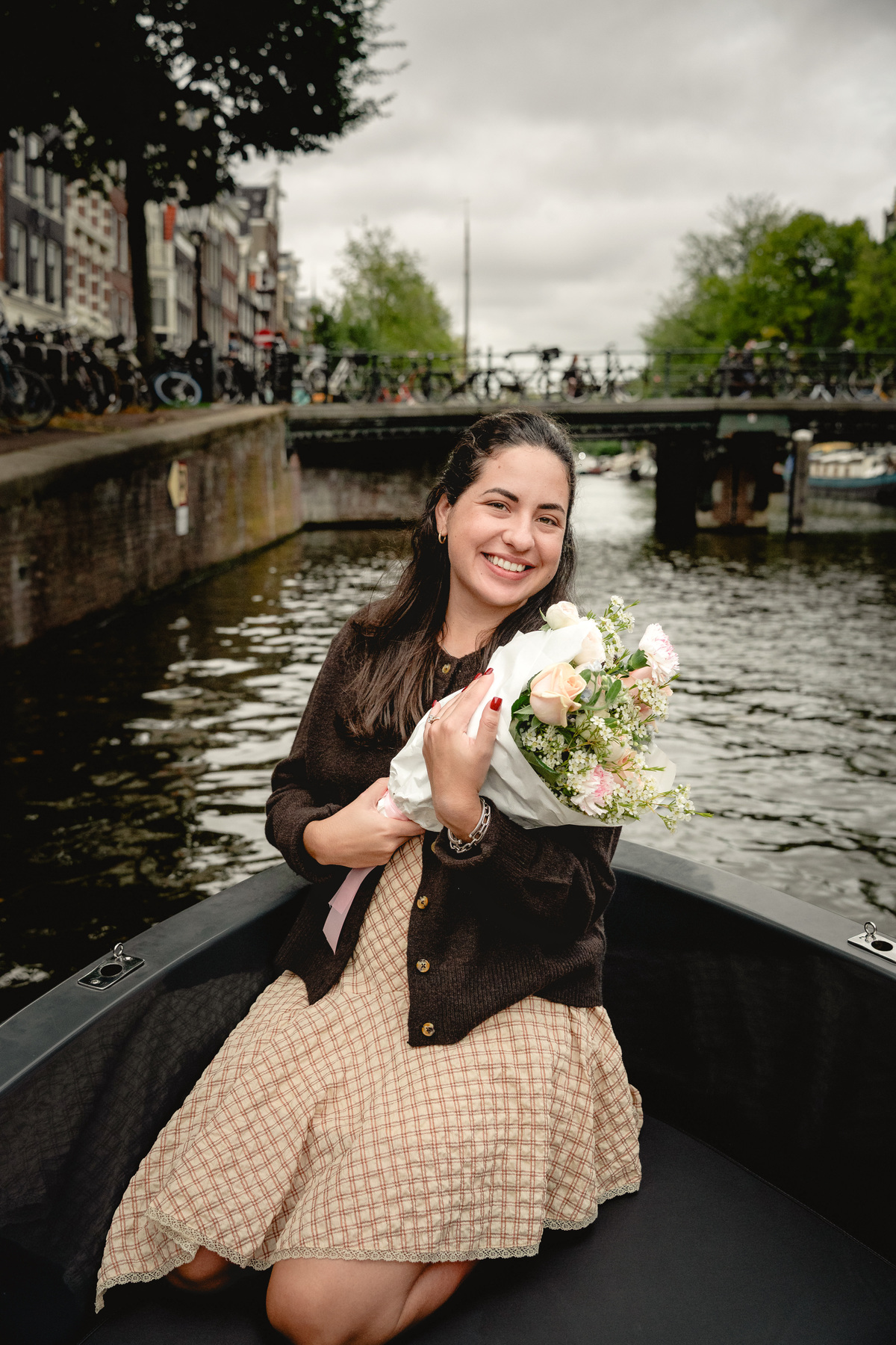 Woman holding her proposal flowers on an Amsterdam boat.

