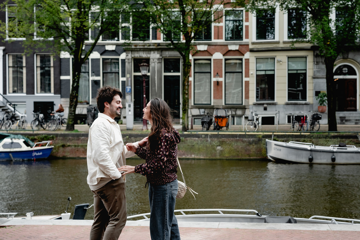 Couple standing together beside an Amsterdam canal before their surprise proposal.