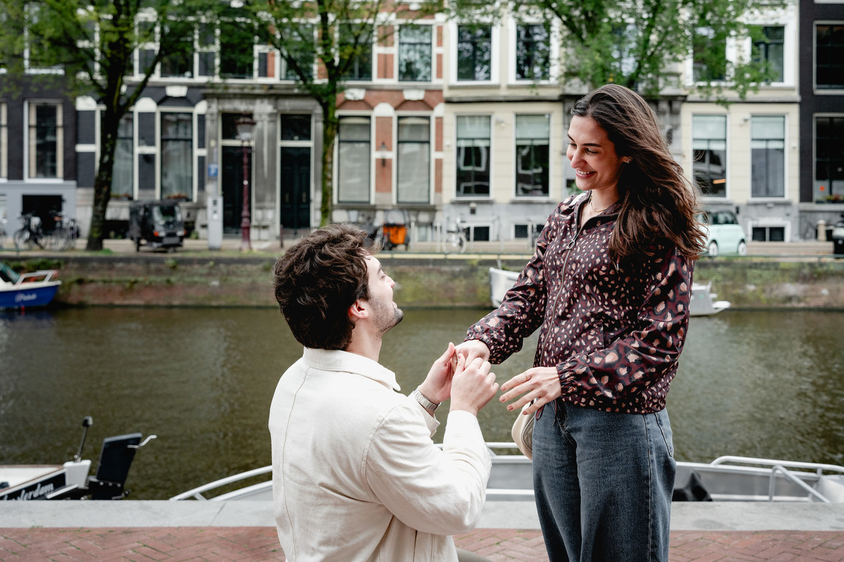 Woman reacting as her partner proposes beside the canal in Amsterdam.