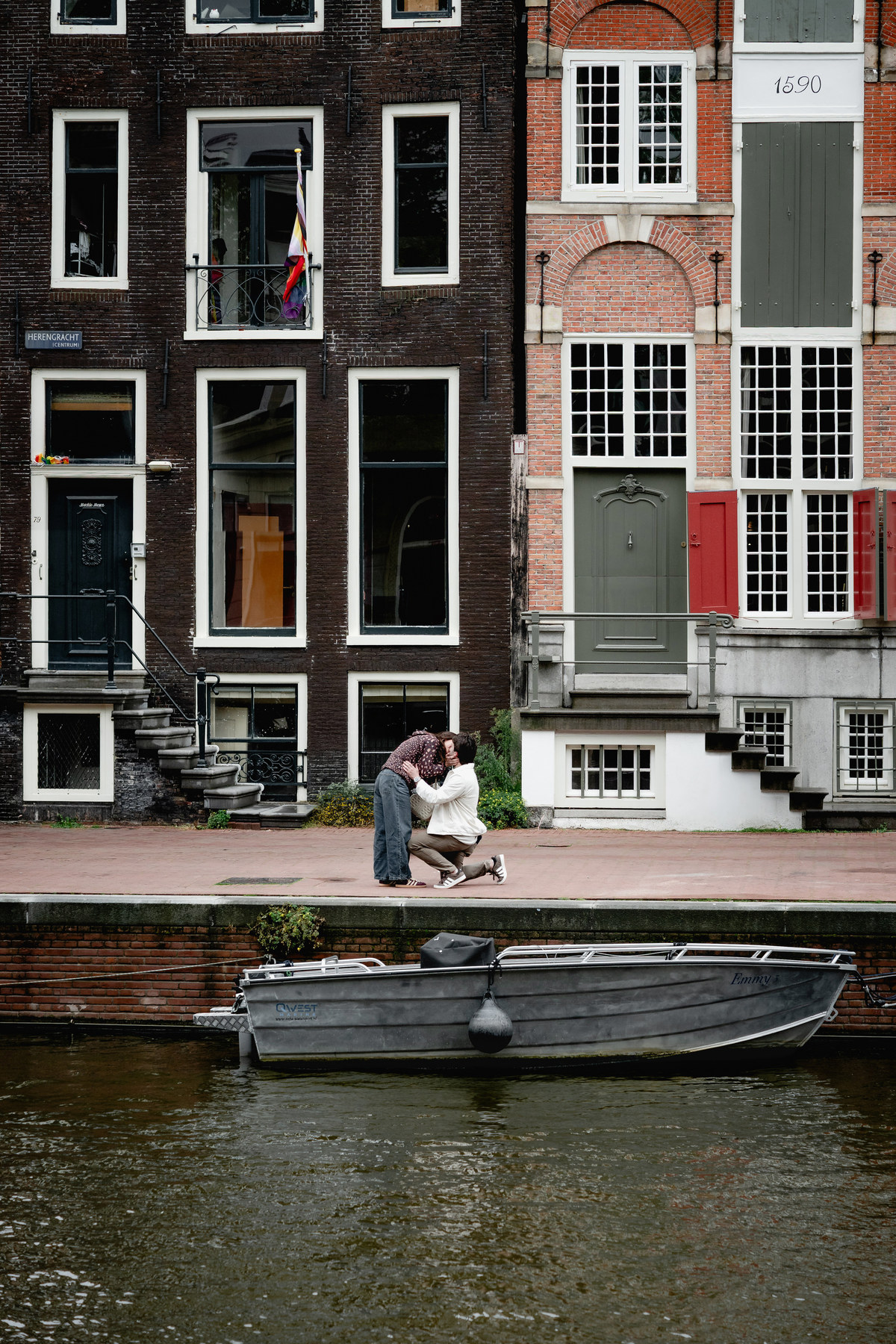 Surprise proposal beside tall historic canal houses in Amsterdam.