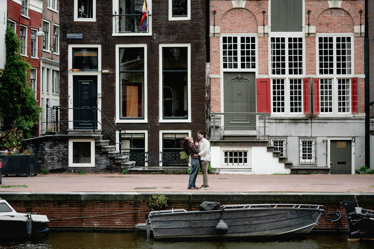 Couple sharing a quiet moment beside Amsterdam canal houses.
