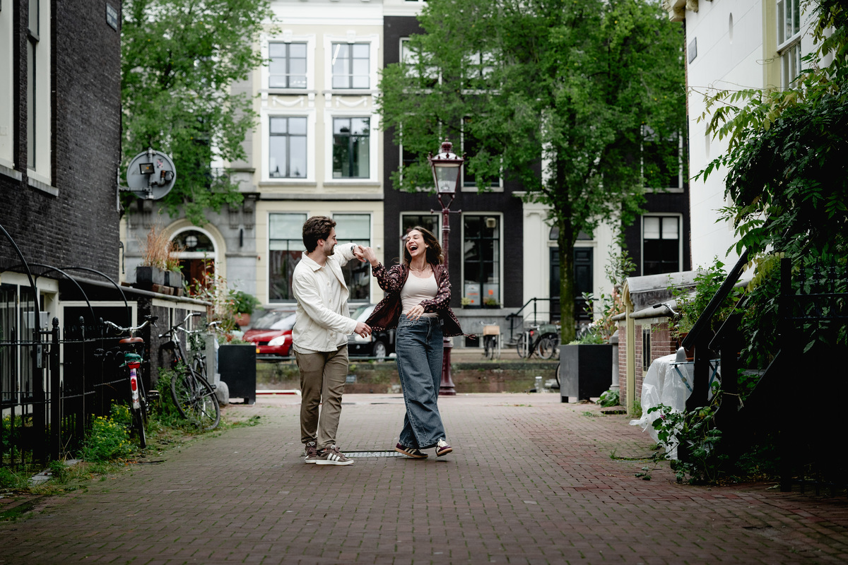 Newly engaged couple walking through a quiet Amsterdam street.