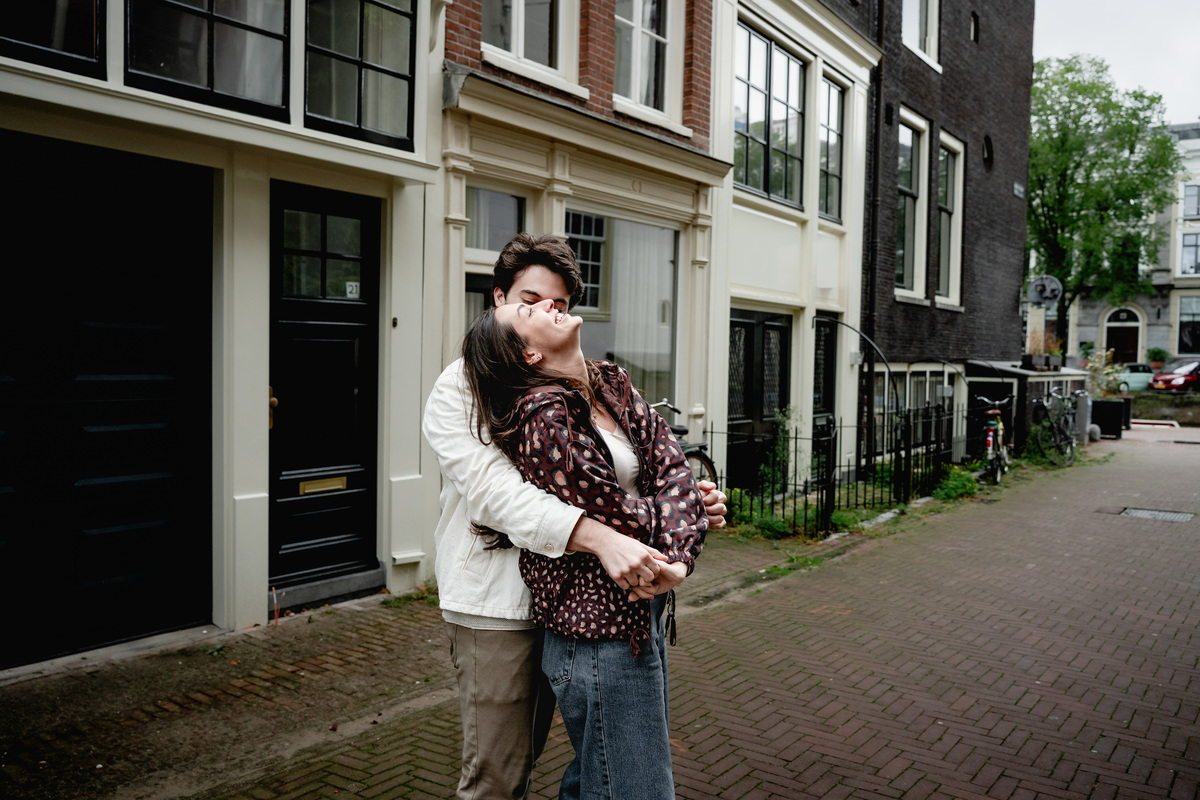 Couple hugging together on a canal-side street in Amsterdam.
