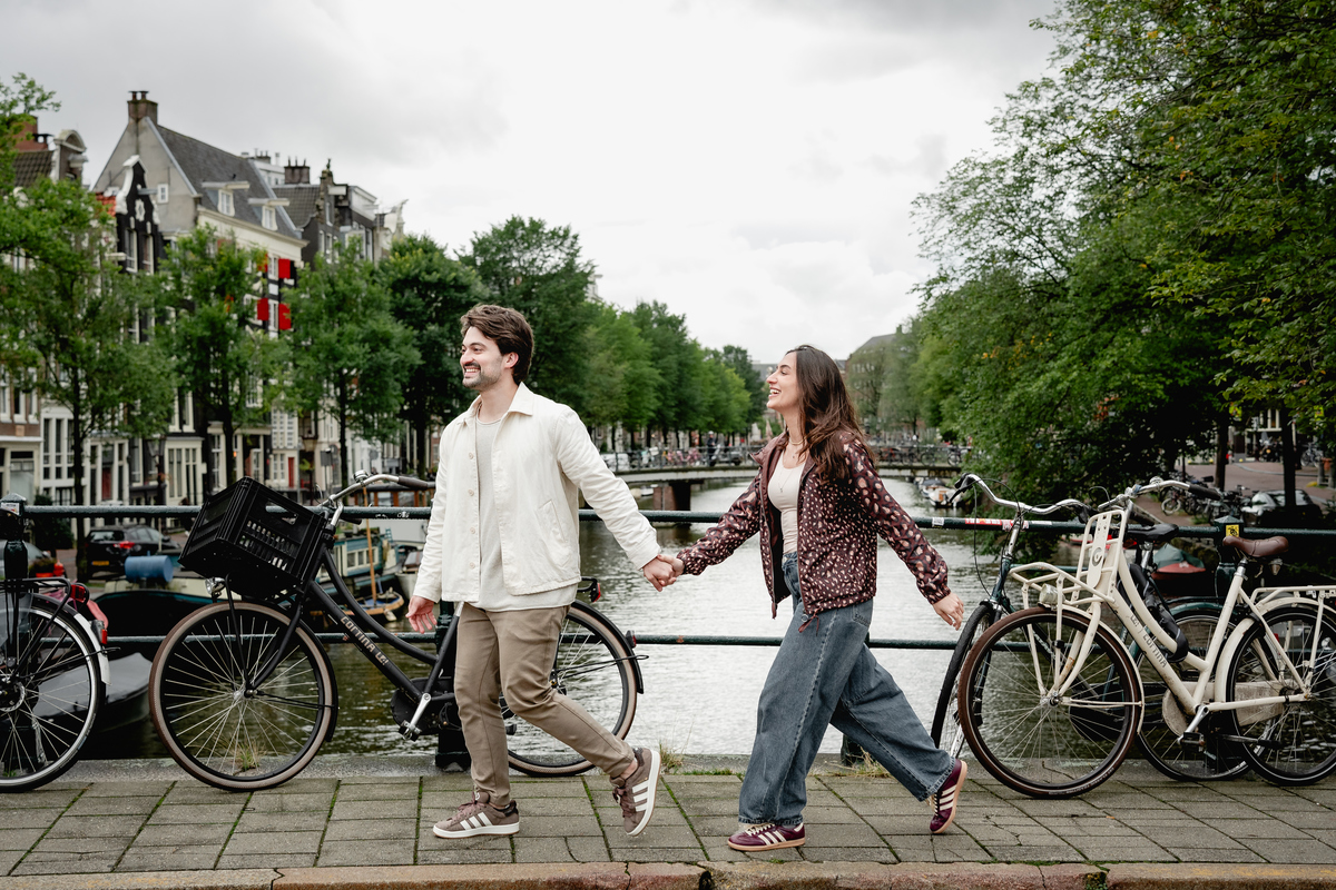 Engaged couple walking hand in hand beside an Amsterdam canal.