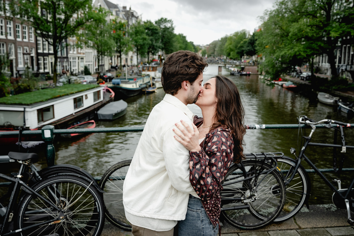 Couple kissing beside bicycles and canal houses in Amsterdam.
