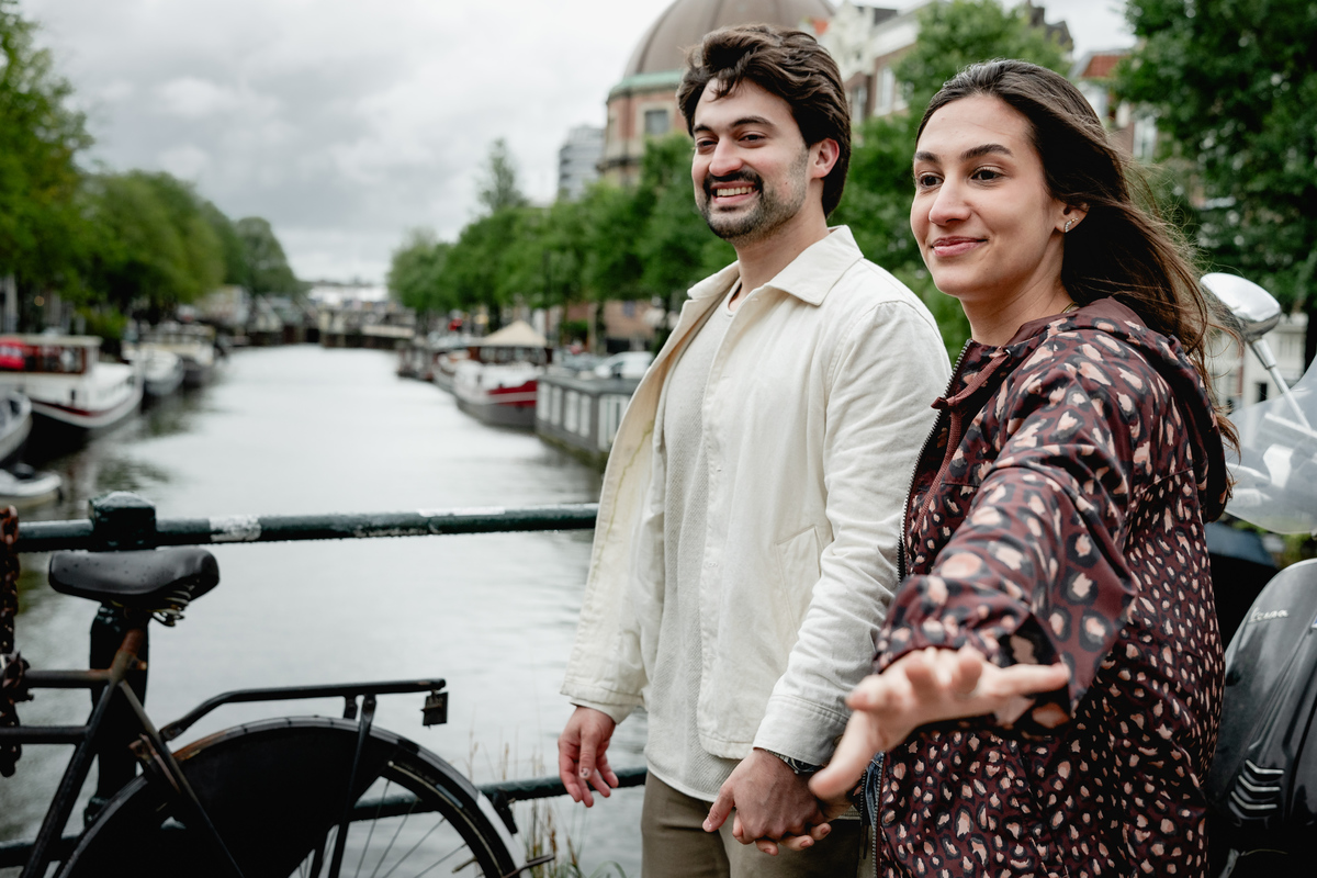 Newly engaged couple smiling together beside an Amsterdam canal.