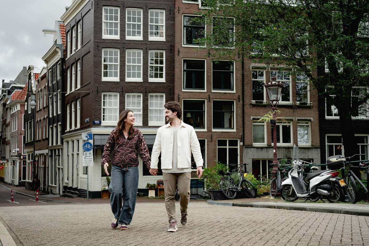 Couple walking past historic canal houses in Amsterdam.