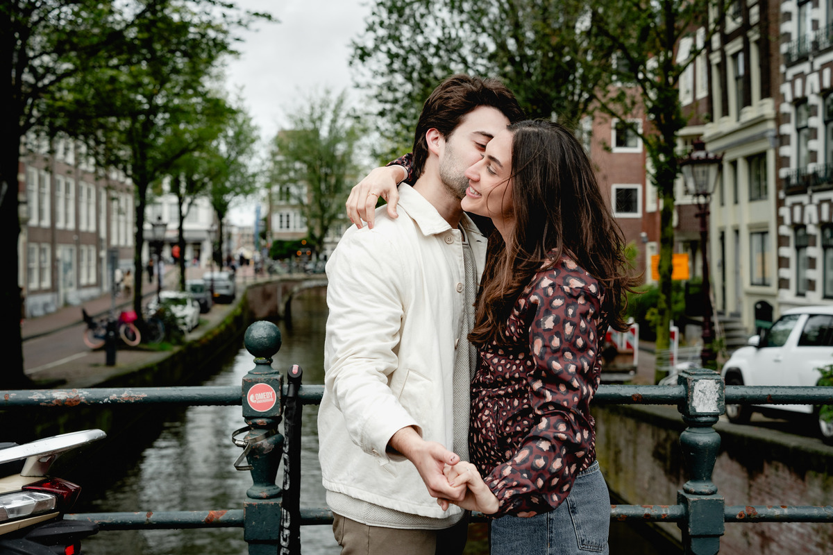 Couple embracing beside an Amsterdam canal after their proposal.