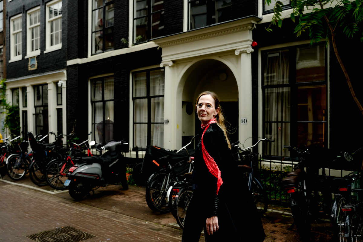 Solo portrait of a woman beside an Amsterdam canal with bicycles and canal houses.