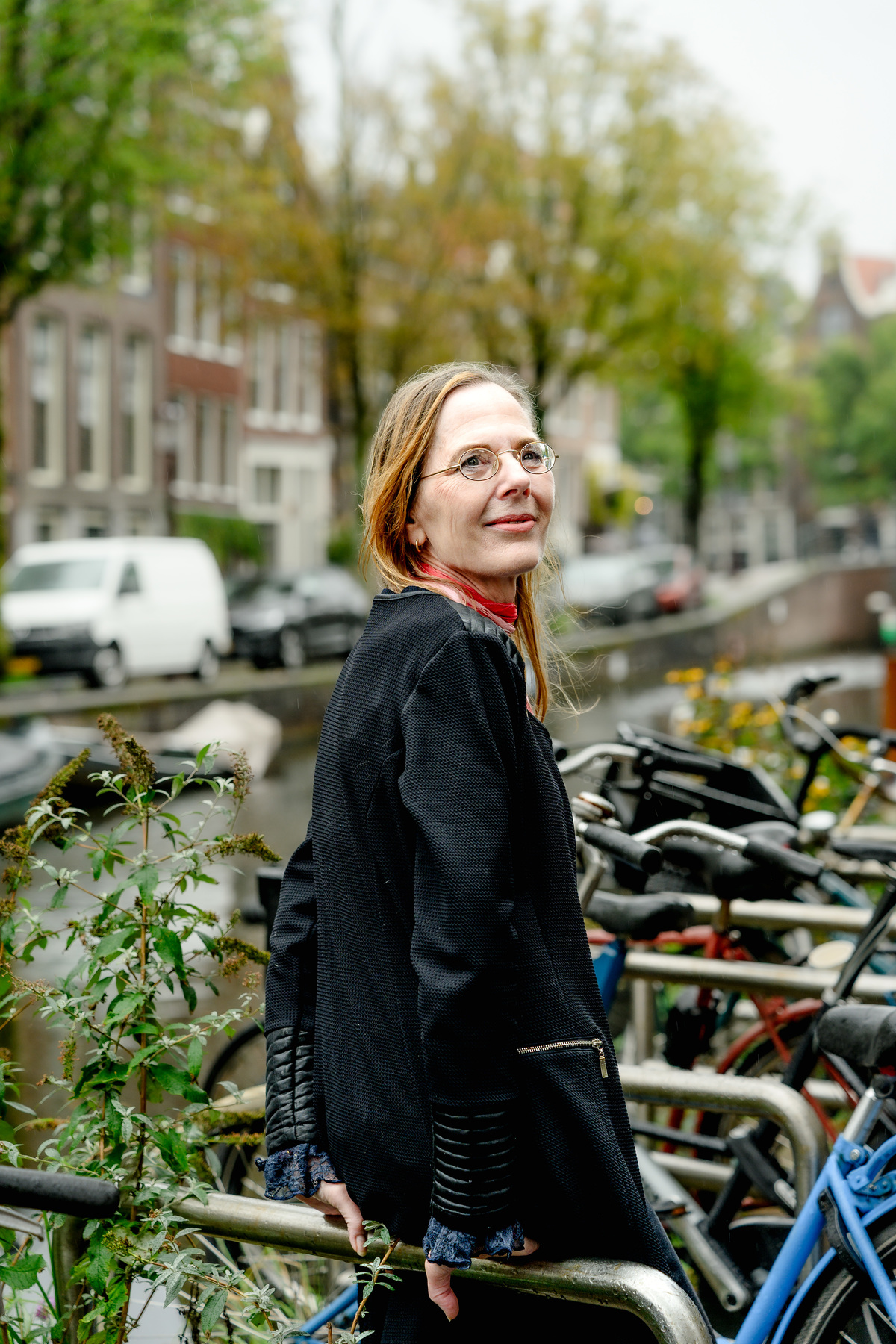 Woman smiling during a relaxed solo photo session beside an Amsterdam canal.