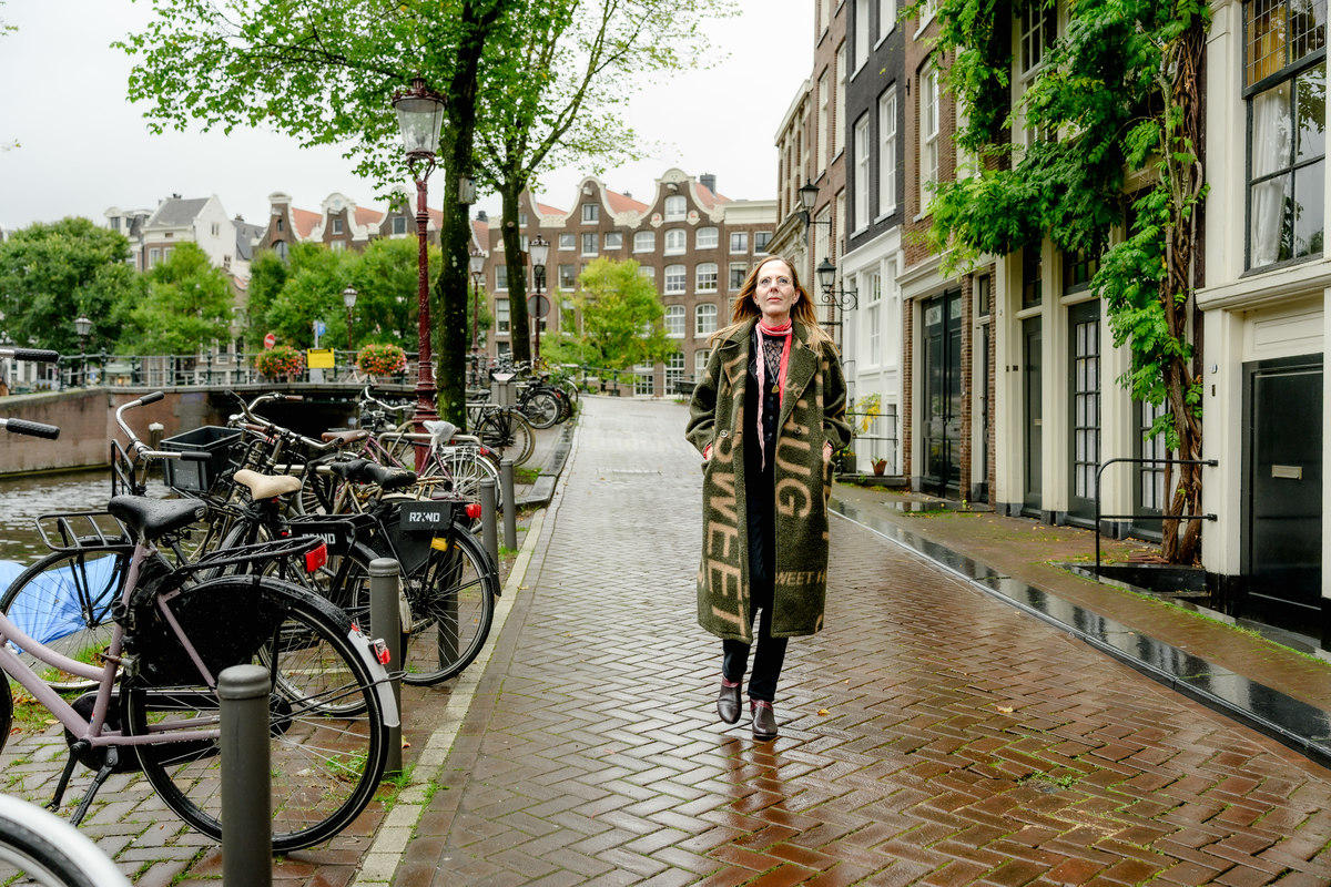 Woman walking alone along a quiet canal street in Amsterdam.