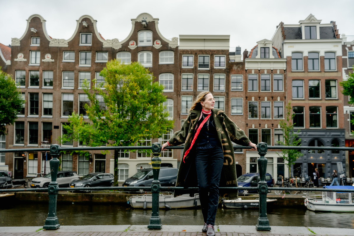 Woman standing beside canal houses during an editorial photo session in Amsterdam.