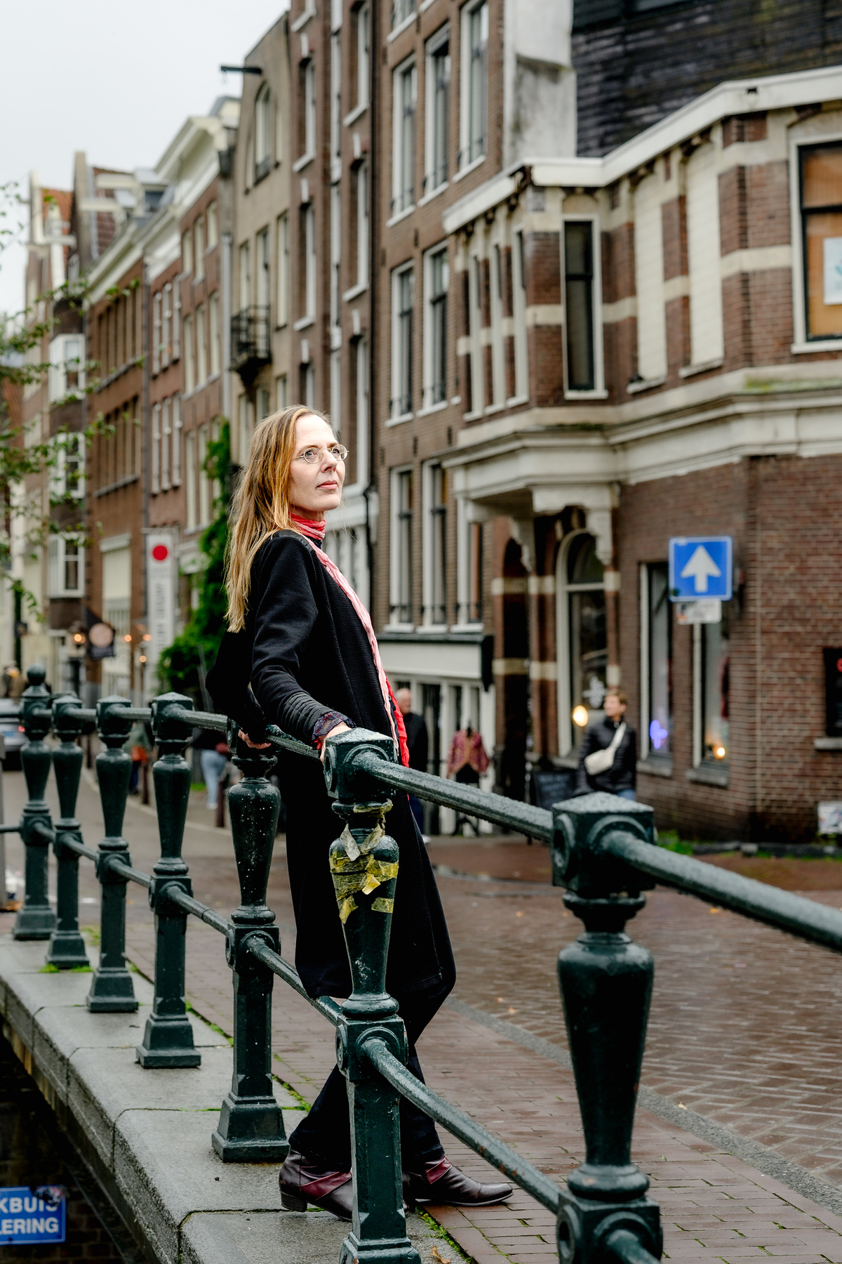 Woman standing beside a canal bridge in Amsterdam.