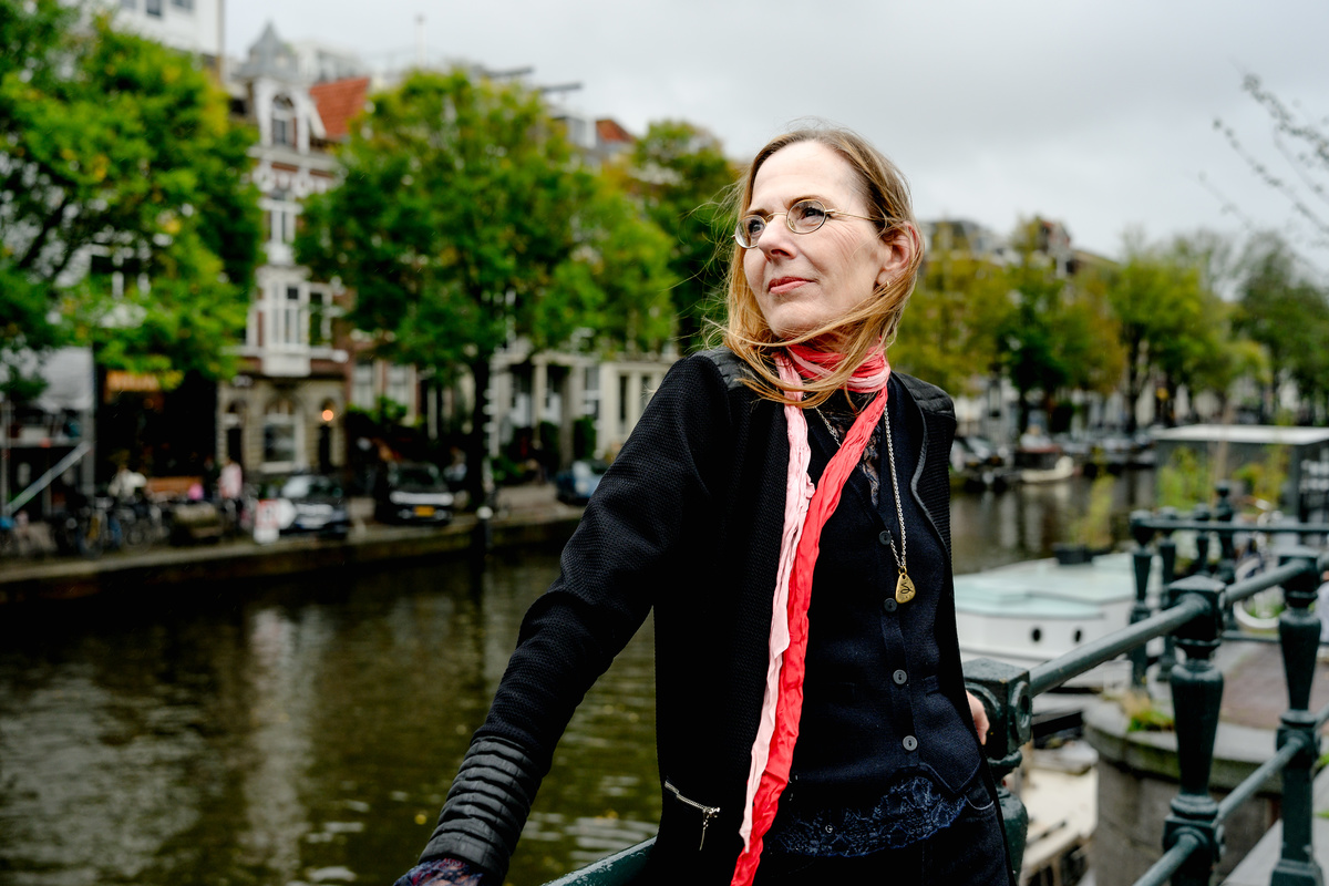 Woman smiling beside the canal during a relaxed Amsterdam portrait session.
