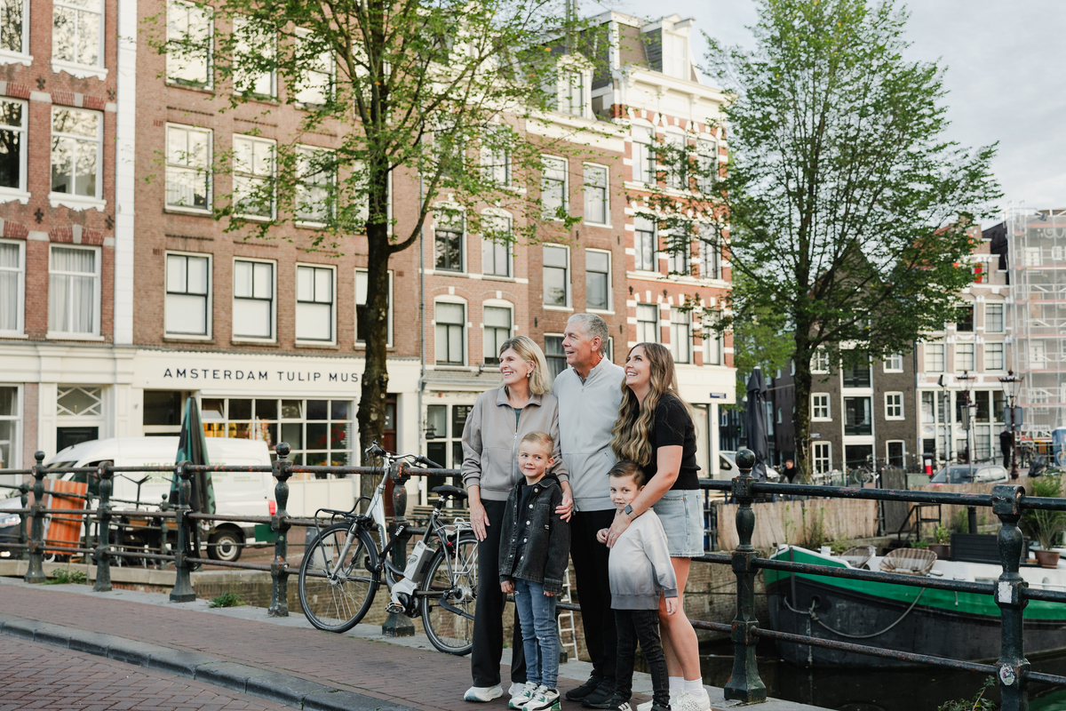 Multi-generational family portrait with Amsterdam canal houses behind them.