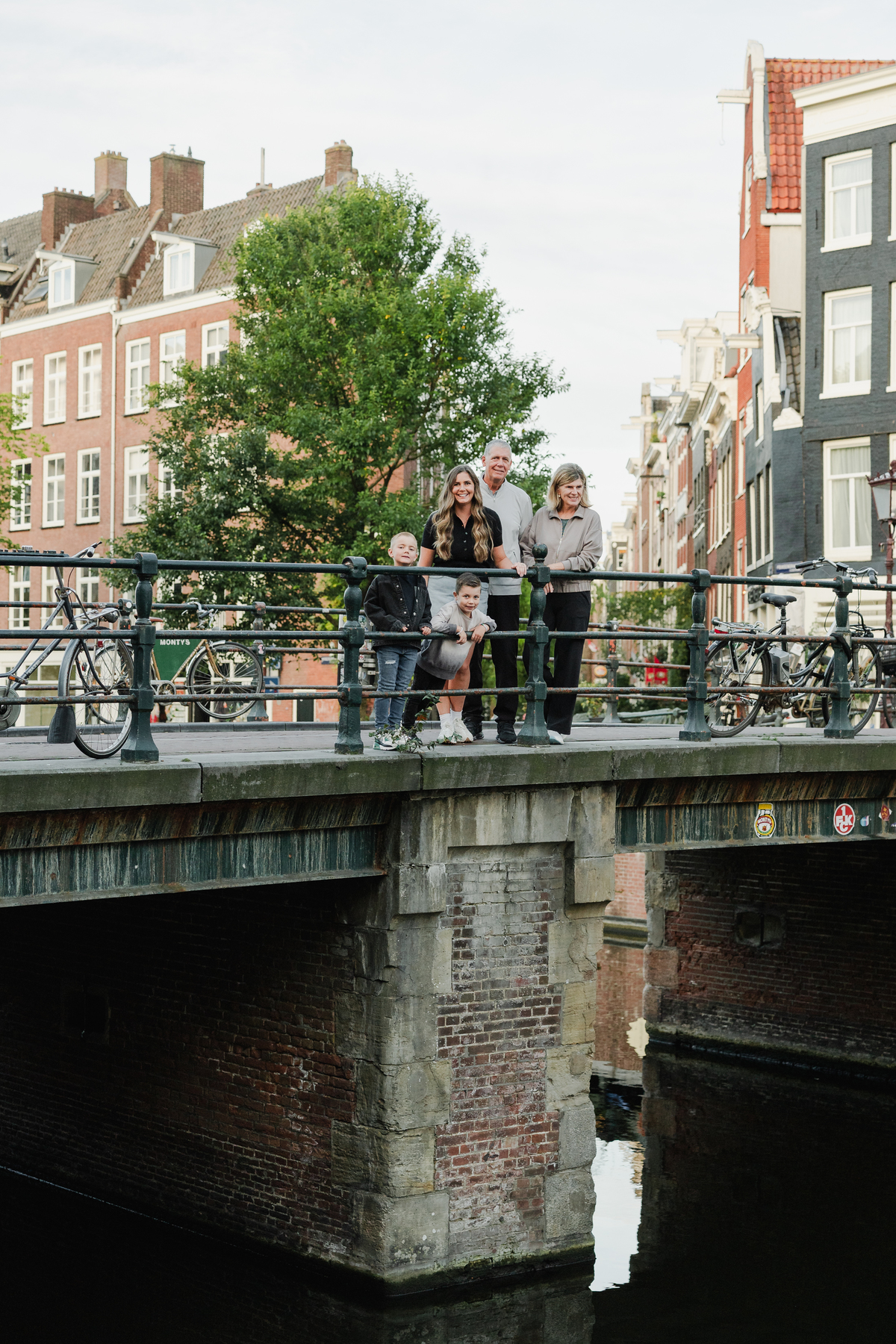 Family standing together on a canal bridge in the Jordaan.