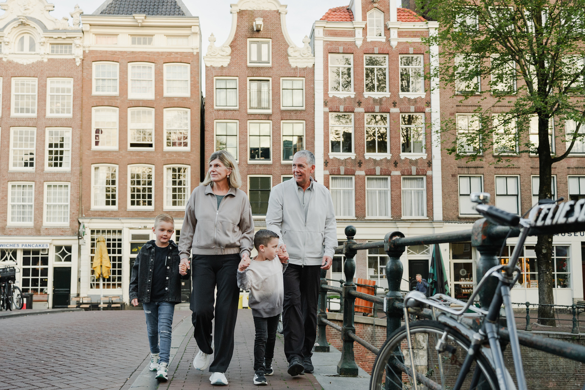 Family portrait beside canal houses and bicycles in Amsterdam.