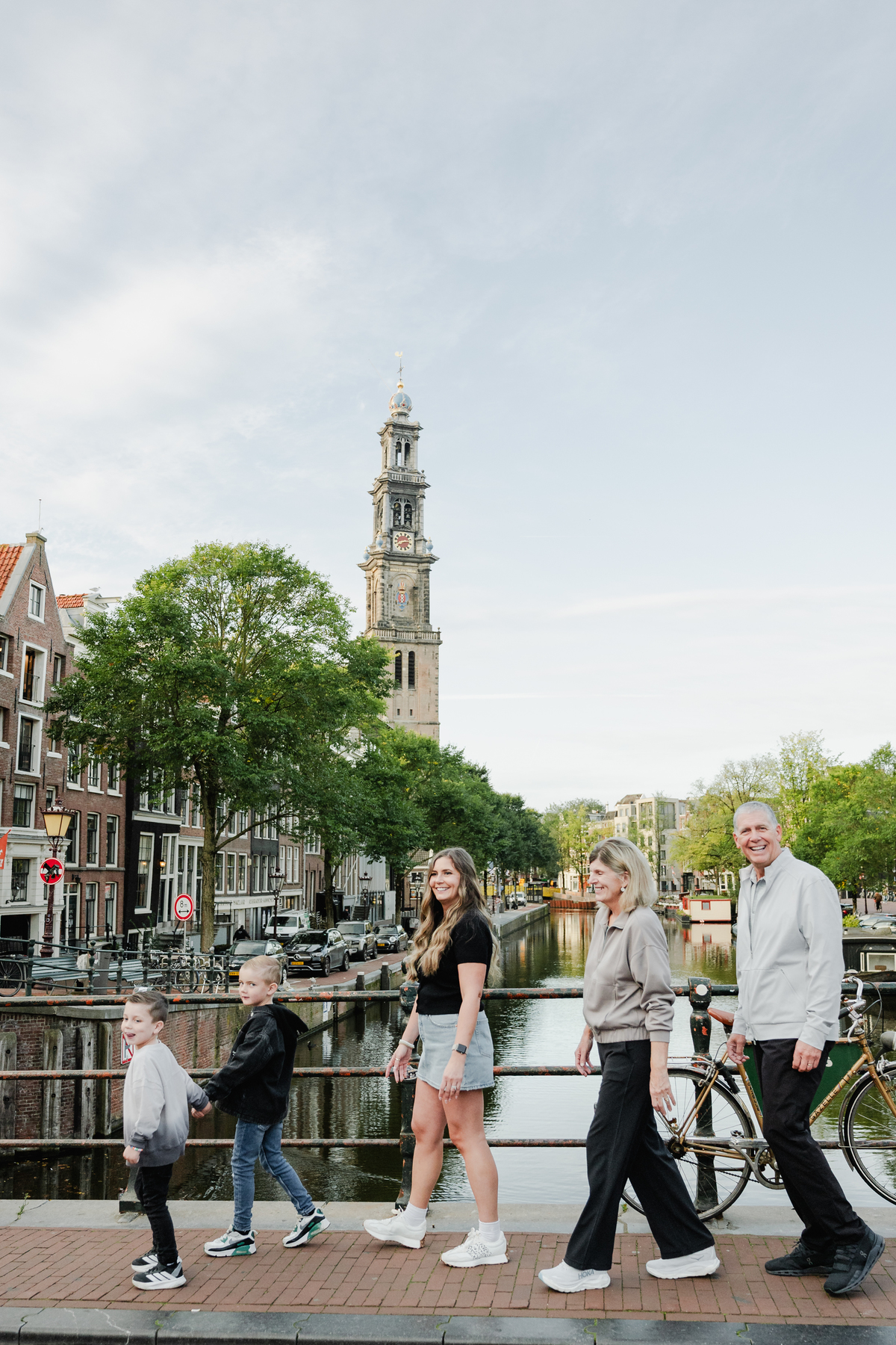 Family walking through the Jordaan with Amsterdam canal houses behind them.