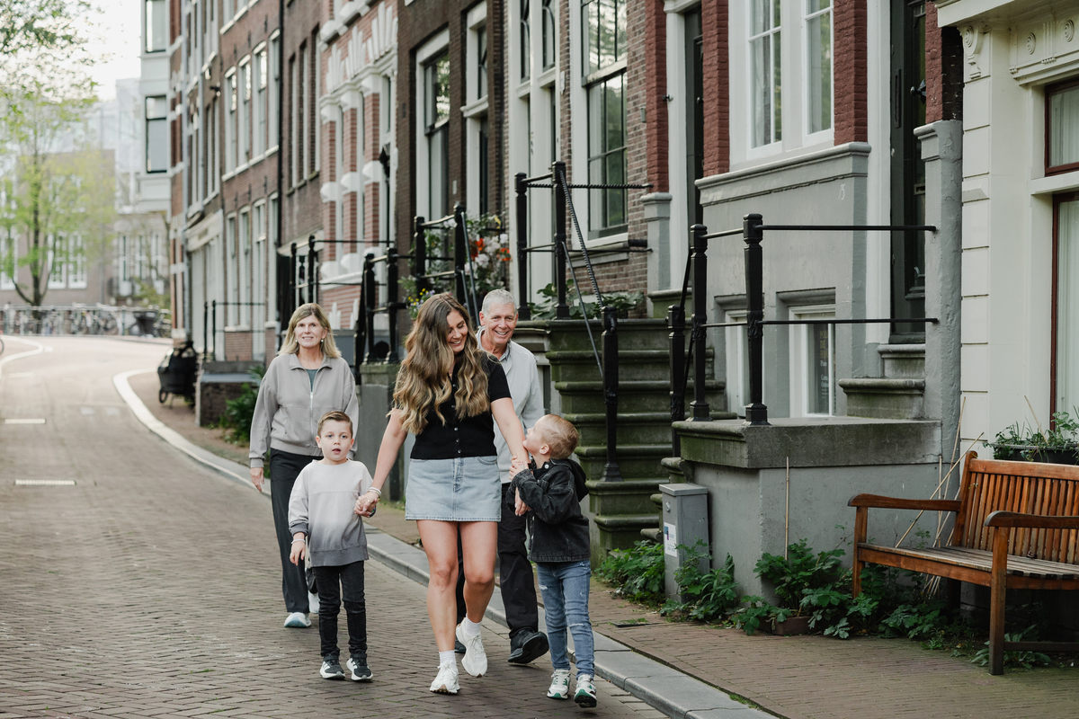 Family walking through the Jordaan with Amsterdam canal houses behind them.