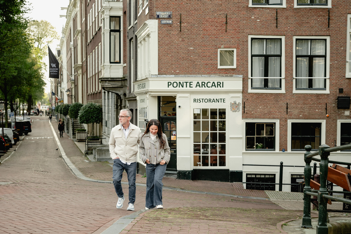 Couple standing together on a canal street during their first visit to Amsterdam.
