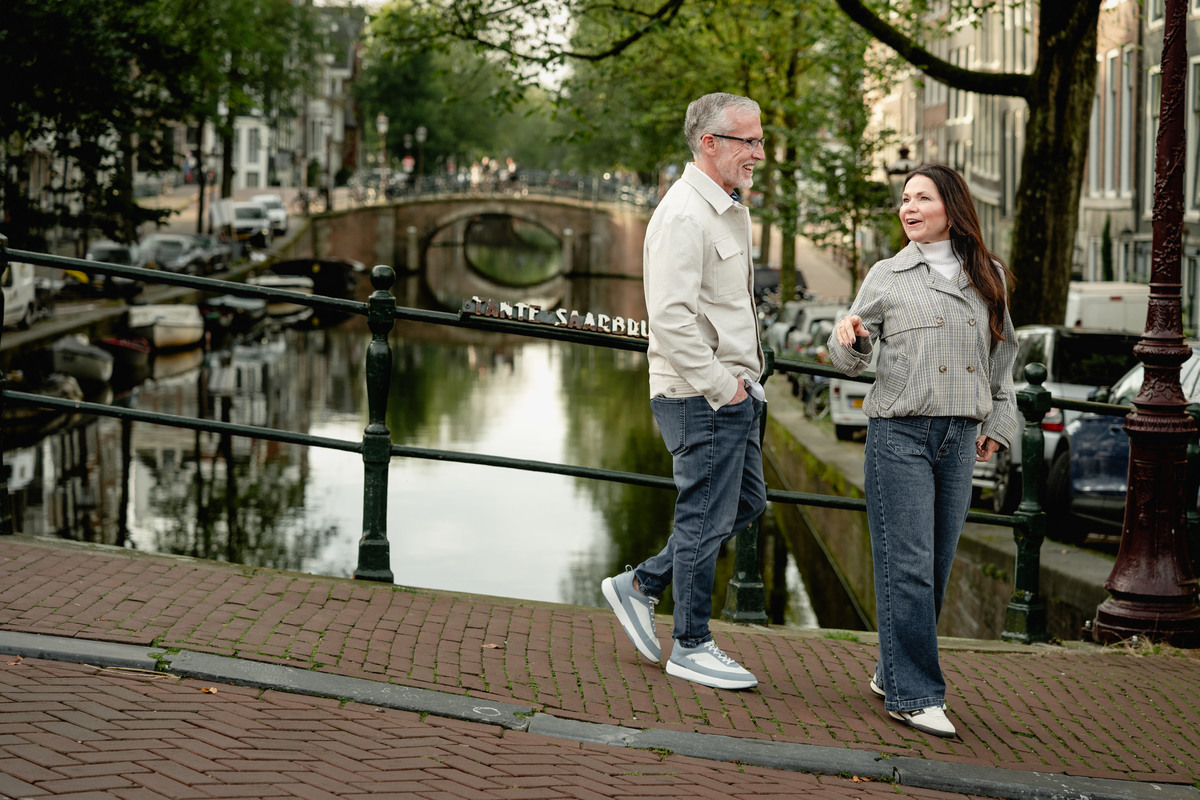 Couple walking hand in hand along a canal in Amsterdam.