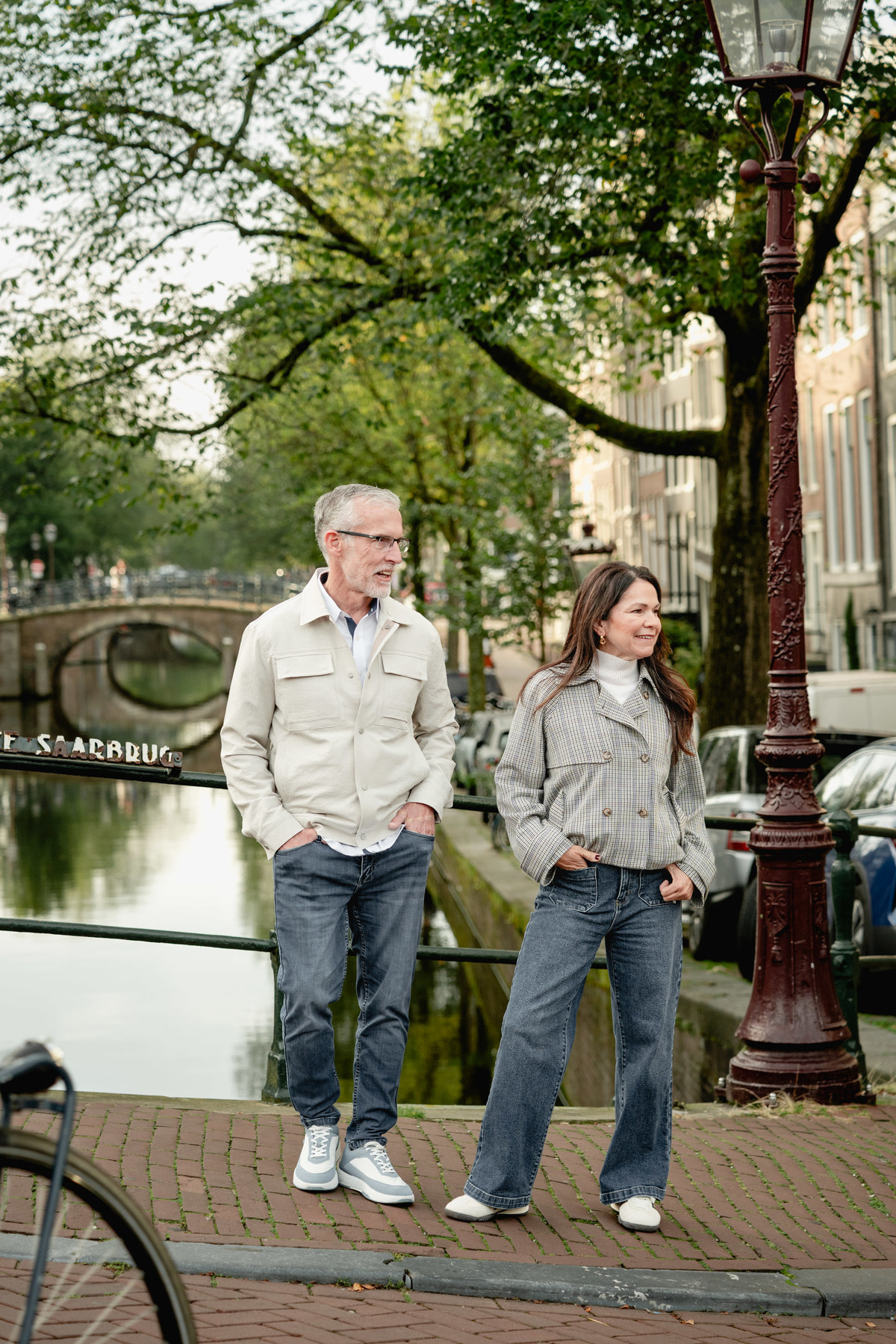 Couple walking together beside bicycles and canal houses in Amsterdam.