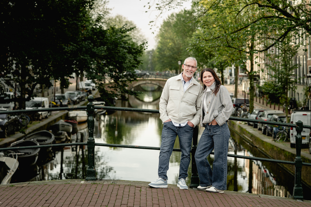 Couple sitting together beside an Amsterdam canal during a relaxed photo session.