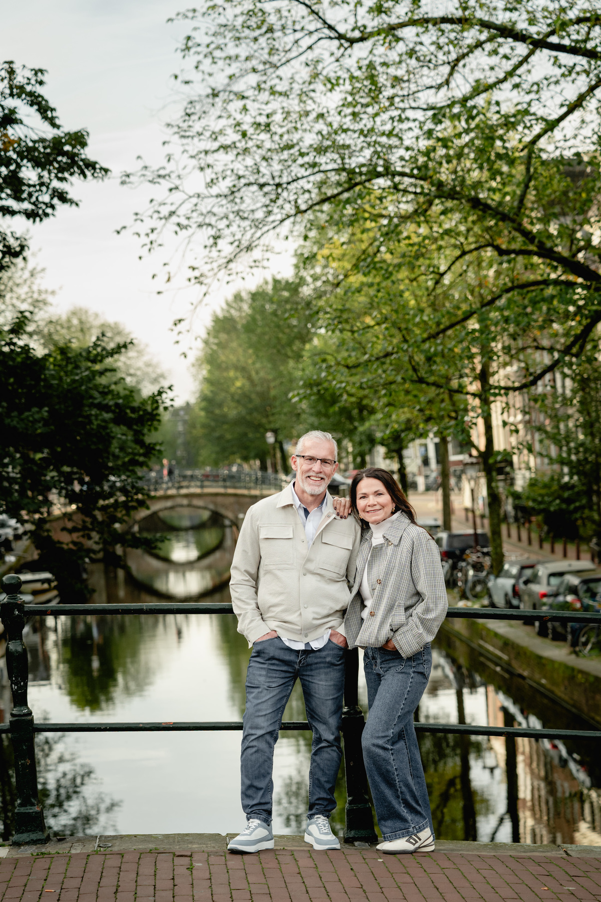Couple standing close together on a canal bridge in Amsterdam.