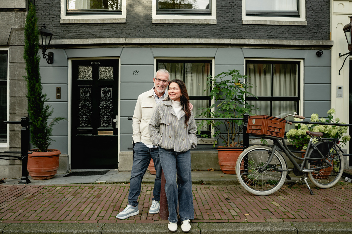 Couple standing beside bicycles in front of an Amsterdam canal house.