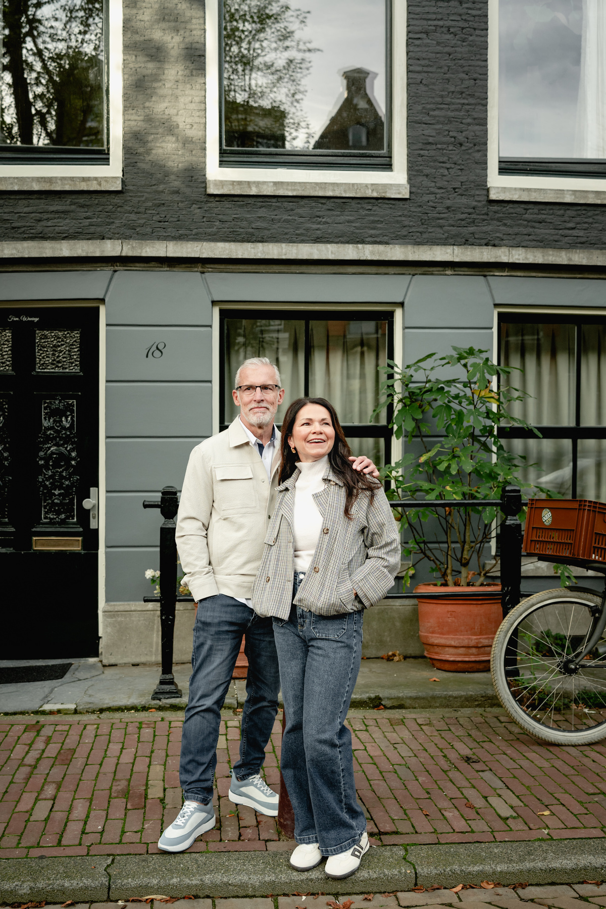 Couple embracing outside a traditional Amsterdam house and bicycles.