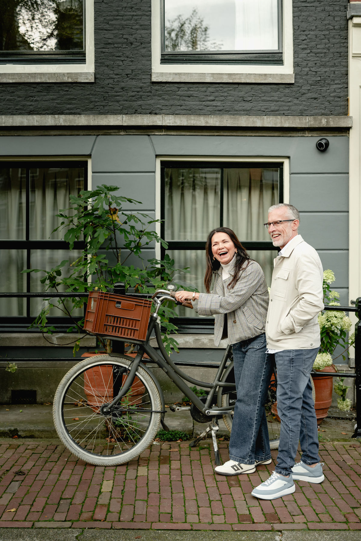Couple holding hands beside a canal house during their Amsterdam photo session.