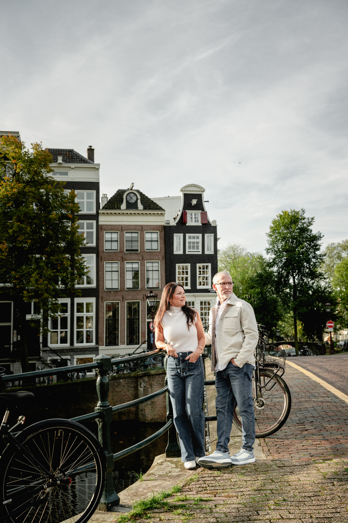 Couple standing beside bicycles on a quiet residential street in Amsterdam.