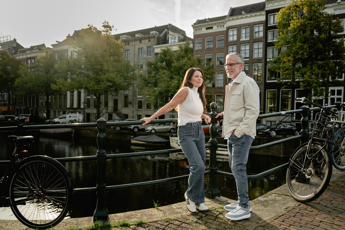 Couple walking together beside an Amsterdam canal with bicycles in the foreground.