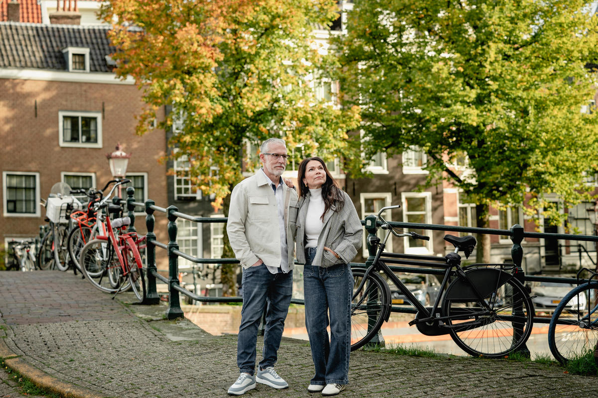 Couple standing together beside bicycles and a canal during their Amsterdam visit.