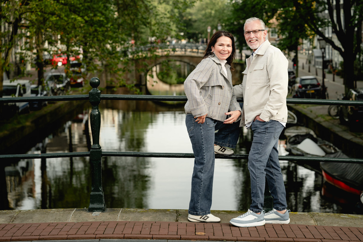 Couple standing together on a small bridge above an Amsterdam canal.