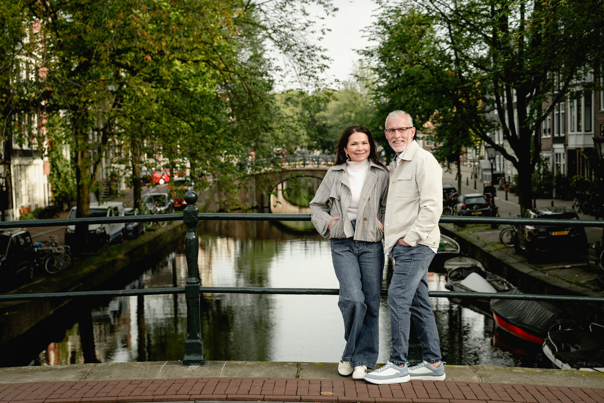 Couple holding each other on a canal bridge in Amsterdam.