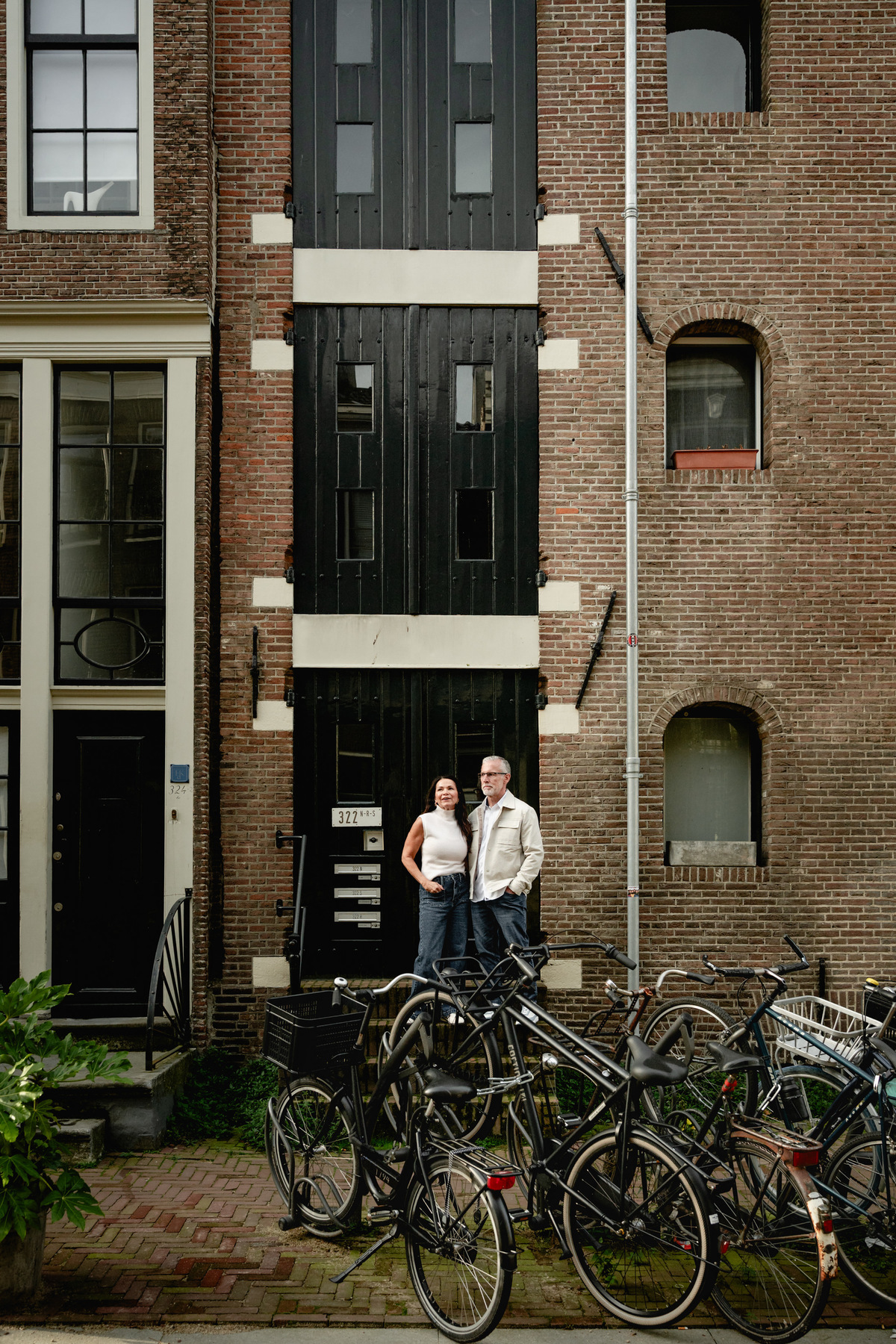 Couple photographed from across a quiet Amsterdam street with bicycles in the foreground.