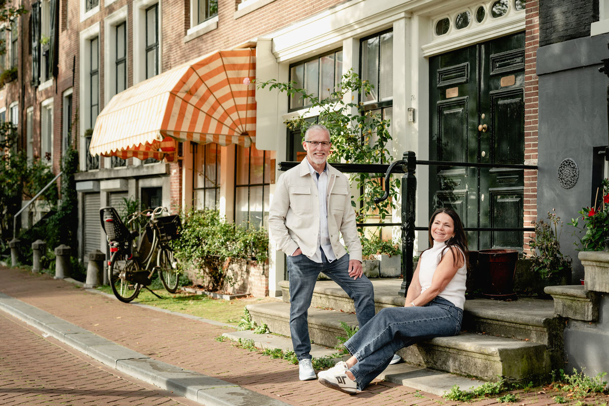 Couple sitting together outside a canal house during their Amsterdam photo session.