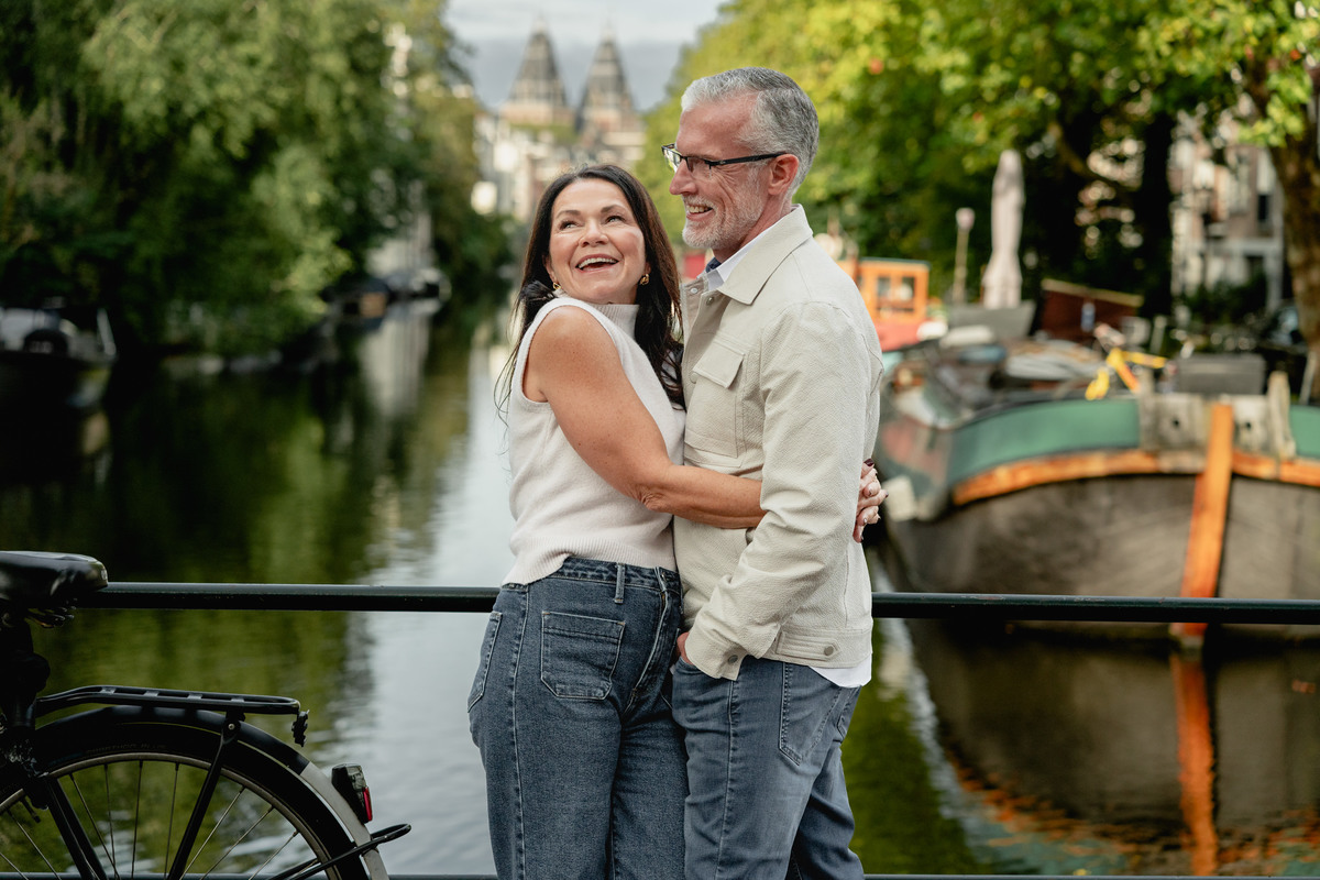 Couple holding each other beside a canal and bicycles in Amsterdam.