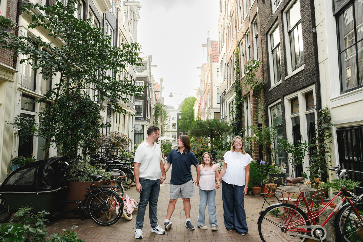 Family walking together on a quiet street with bicycles and canal houses in Amsterdam.