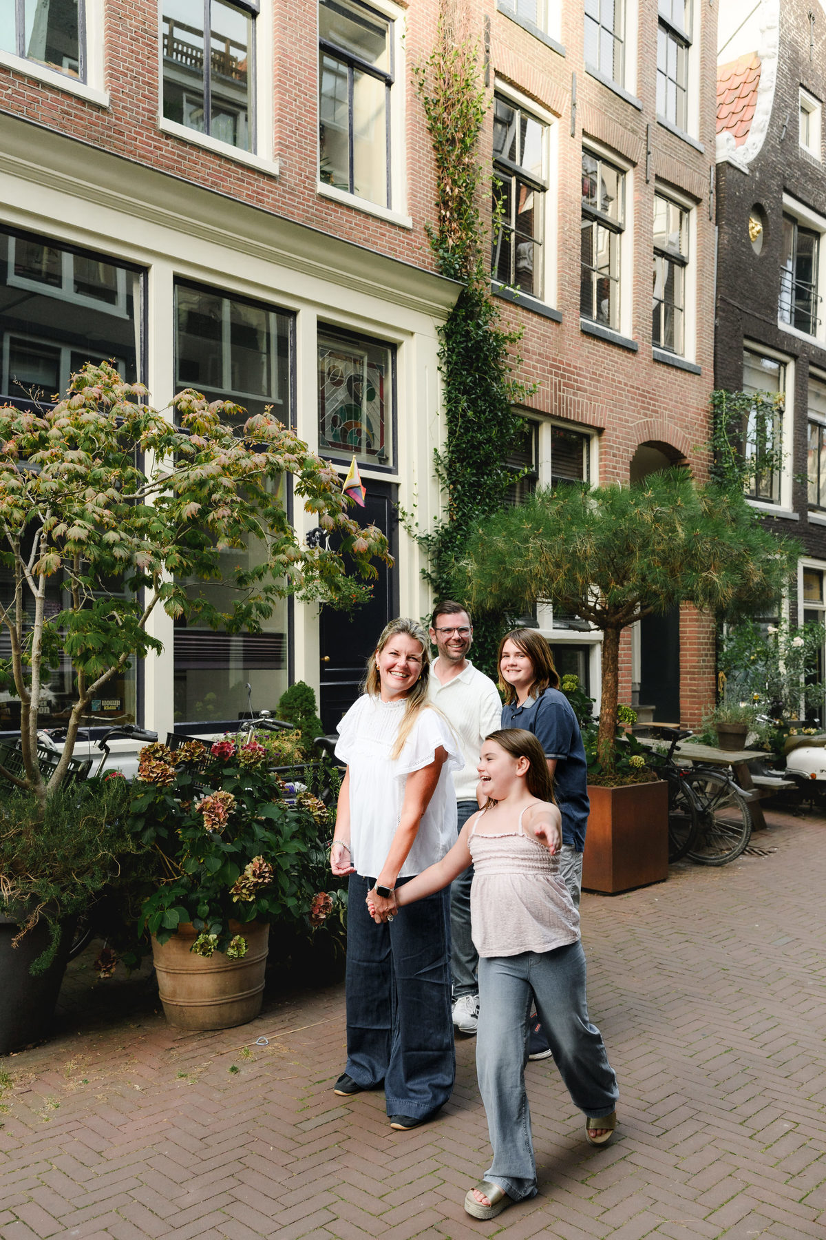 Parents and children standing together outside traditional Amsterdam canal houses