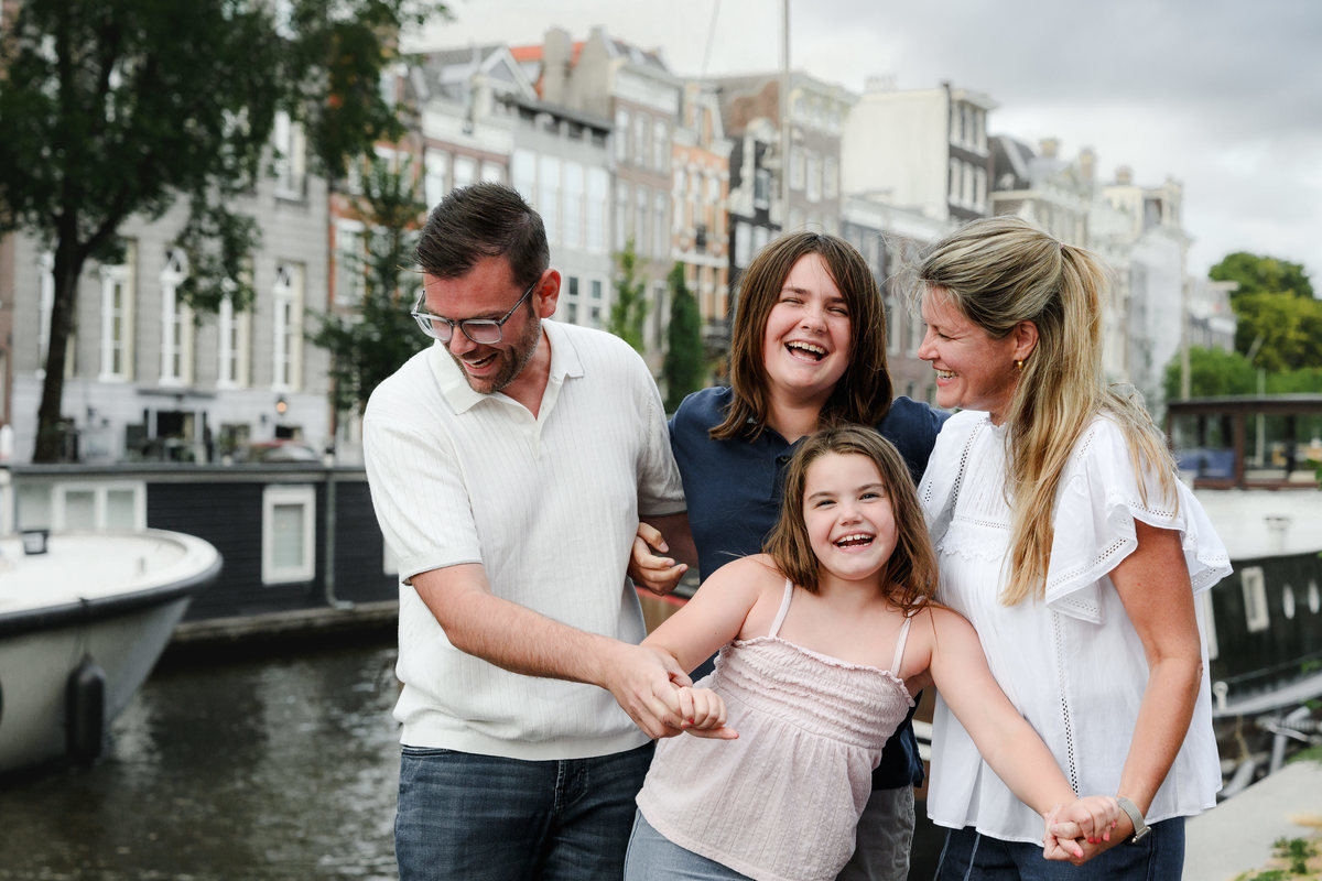 Parent and children laughing together beside an Amsterdam canal.