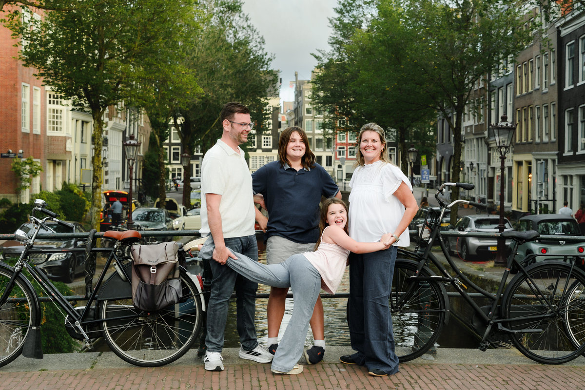 Family standing together beside bicycles along an Amsterdam canal.