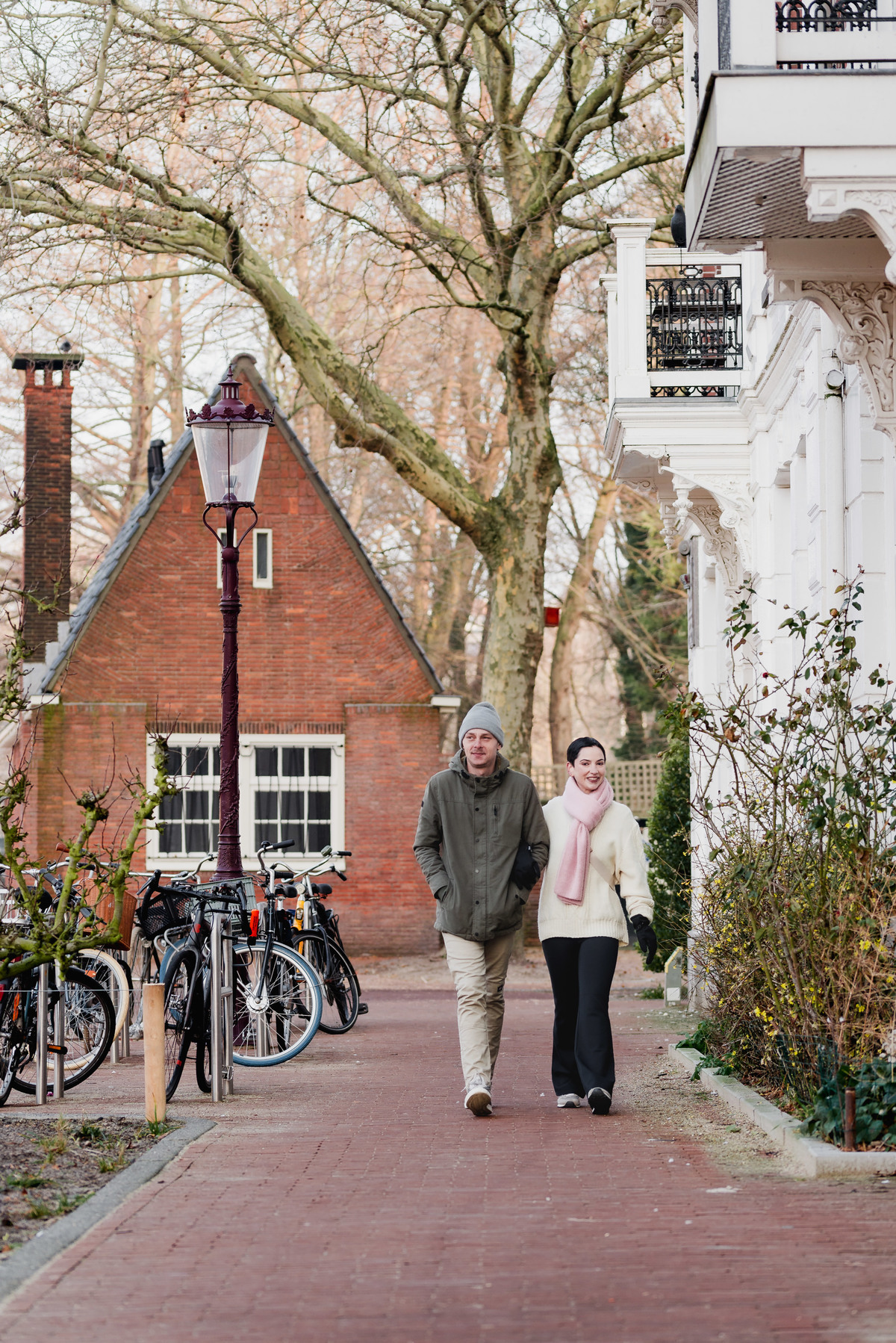 Couple standing together between historic houses during a winter photo session in Amsterdam.