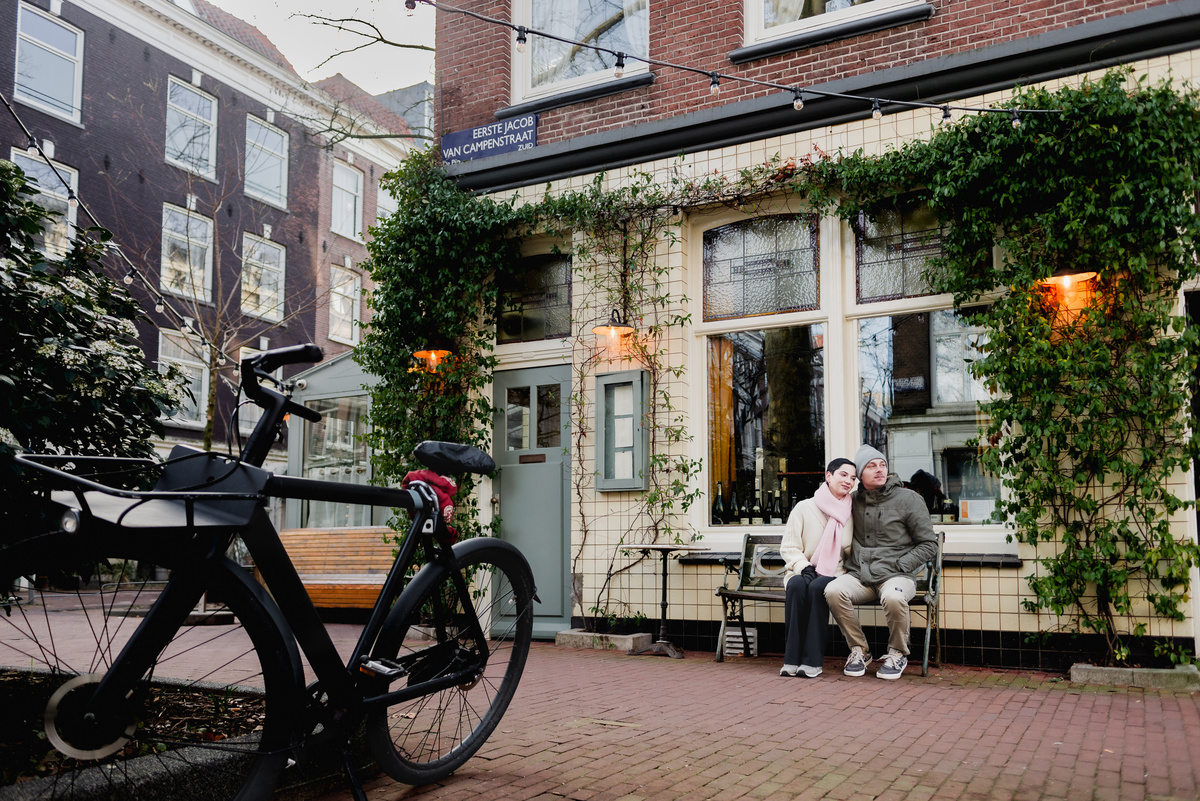 Couple walking beside bicycles on a quiet Amsterdam street.