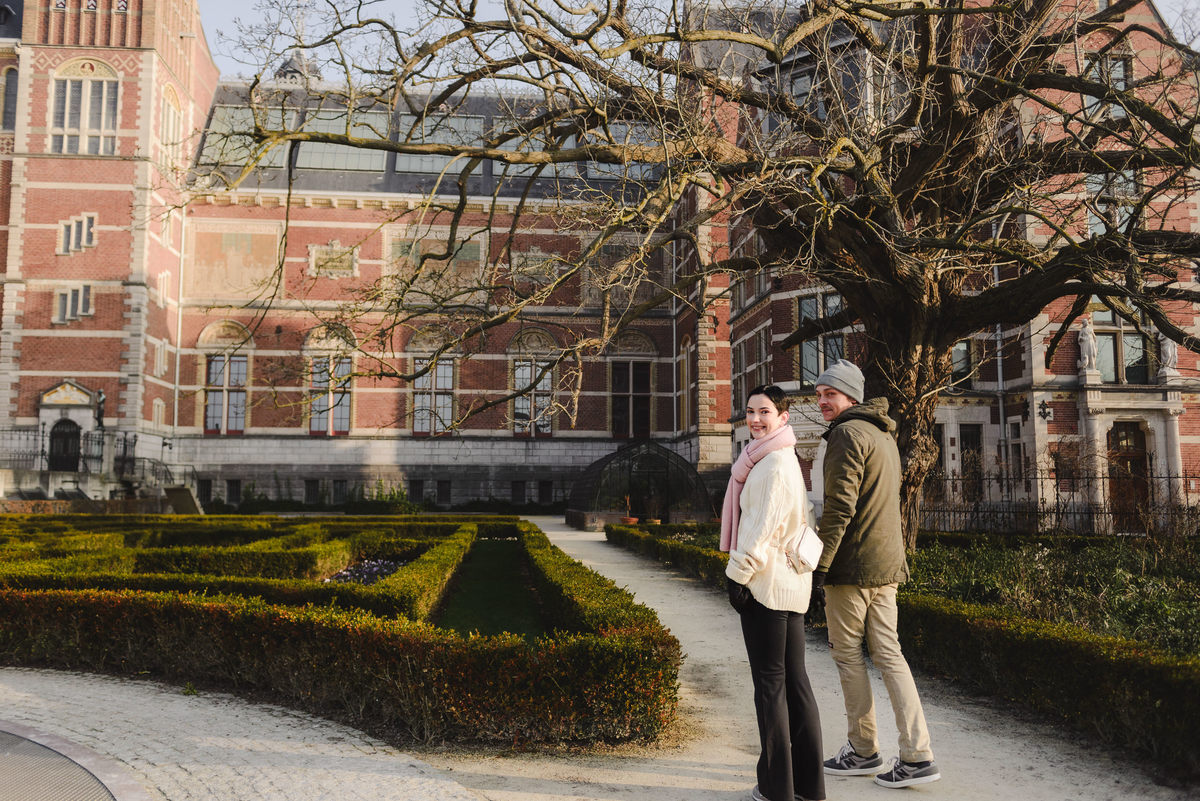 Couple walking together beside historic Amsterdam buildings.