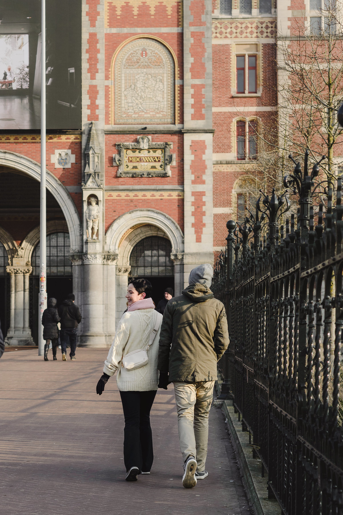 Couple walking beside the Rijksmuseum during a winter photo session in Amsterdam.