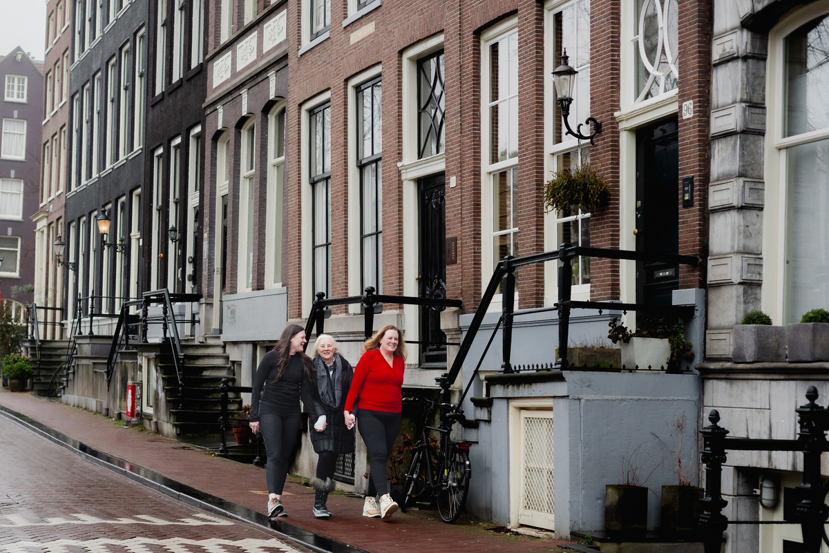 Three women walking along a quiet canal street in Amsterdam.
